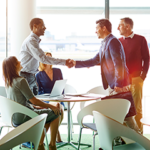 Men shaking hands over table